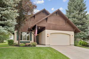 View of front of home with a front yard, stucco siding, driveway, and an attached garage
