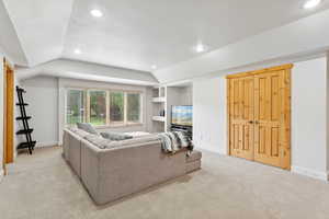 Living area featuring vaulted ceiling, light carpet, recessed lighting, and built in features