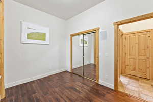 Unfurnished bedroom with wood finished floors and a closet