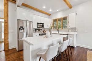 Kitchen featuring stainless steel appliances, beam ceiling, backsplash, dark wood-type flooring, and recessed lighting