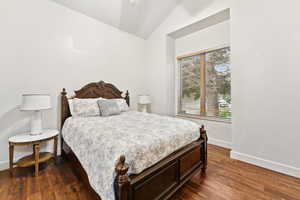 Bedroom featuring lofted ceiling and dark wood-style flooring