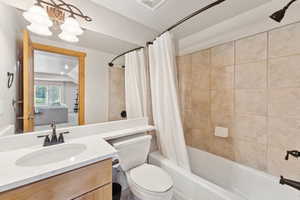 Bathroom featuring shower / bath combo, vanity, and a chandelier