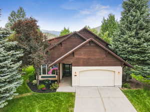 View of front facade featuring a garage, driveway, a front lawn, and stucco siding