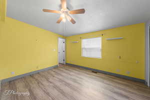 Empty room with wood finished floors, a textured ceiling, and a ceiling fan