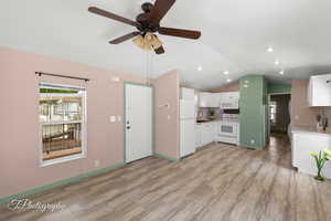 Unfurnished living room with lofted ceiling, light wood-style floors, and a ceiling fan