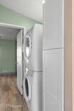 Laundry room featuring stacked washer / dryer and wood finished floors