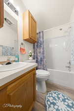 Bathroom featuring wood finished floors, vanity, and shower / tub combo