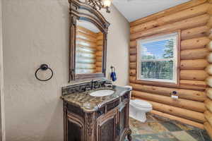 Bathroom with vanity, a textured wall, and log walls