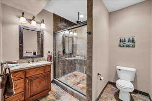 Full bathroom with vanity, a shower stall, a textured wall, and stone tile floors