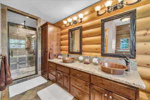 Bathroom featuring log walls, a stall shower, and double vanity