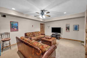 Living room featuring light colored carpet, ceiling fan, a textured ceiling, and recessed lighting