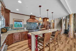 Kitchen featuring island range hood, light wood-style flooring, tasteful backsplash, a center island, and recessed lighting