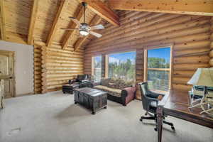 Home office with rustic walls, a wood ceiling with exposed beams, carpet floors, ceiling fan, and high vaulted ceiling