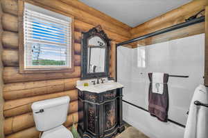 Full bath featuring rustic walls, vanity, and combined bath / shower with glass door