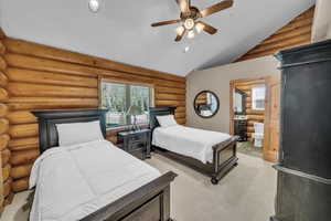 Bedroom featuring lofted ceiling, multiple windows, recessed lighting, light carpet, and ensuite bathroom