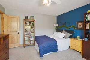 Bedroom featuring light colored carpet, a textured ceiling, and a ceiling fan