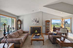Living room with vaulted ceiling, a tile fireplace, carpet, and recessed lighting