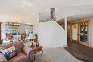 Living area with a chandelier, wood finished floors, stairs, high vaulted ceiling, and french doors