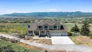 View of front facade featuring driveway, a mountain view, an attached garage, a tiled roof, and covered porch