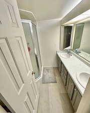 Bathroom with a stall shower, double vanity, and tile patterned flooring