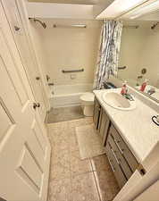 Bathroom with shower / bath combo with shower curtain, vanity, and tile patterned flooring
