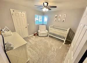 Bedroom with carpet flooring, a crib, and ceiling fan