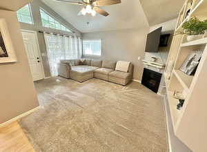 Living area with ceiling fan, a fireplace, and lofted ceiling