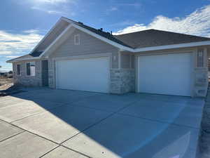 Single story home featuring stone siding, concrete driveway, and a garage