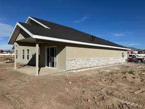 Back of house featuring stucco siding, a patio, and stone siding