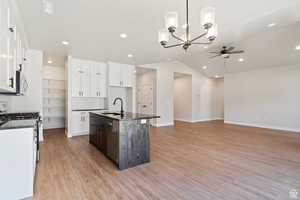 Kitchen with stainless steel appliances, ceiling fan, dark countertops, light wood finished floors, and recessed lighting