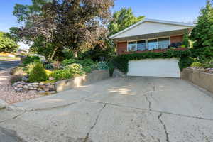 View of front facade featuring brick siding, concrete driveway, a garage, and stairway