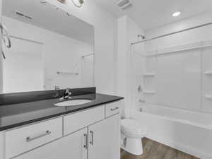 Bathroom featuring wood finished floors, vanity, and bathing tub / shower combination