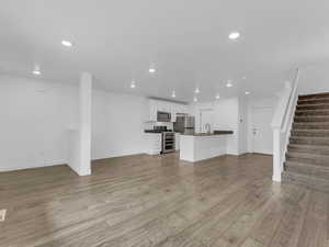 Unfurnished living room with recessed lighting, stairs, and light wood finished floors