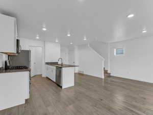 Kitchen with appliances with stainless steel finishes, dark countertops, recessed lighting, white cabinetry, and wood finished floors