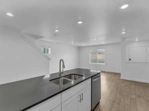 Kitchen with dishwasher, dark countertops, light wood-style flooring, recessed lighting, and white cabinets