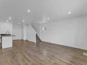 Unfurnished living room featuring recessed lighting, stairway, and wood finished floors
