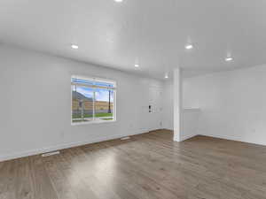 Spare room with wood finished floors and recessed lighting
