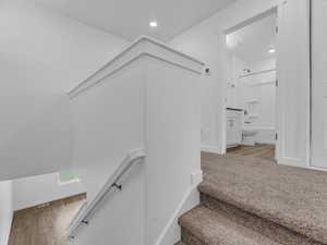 Stairs featuring wood finished floors and recessed lighting