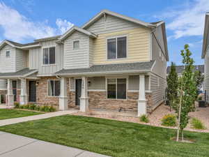 View of front facade with stone siding, a front lawn, and board and batten siding