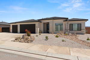 Prairie-style home with a garage, concrete driveway, stucco siding, and a tile roof