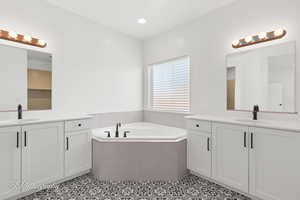 Full bath featuring two vanities, tile patterned flooring, and a garden tub
