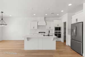 Kitchen with appliances with stainless steel finishes, premium range hood, light countertops, decorative backsplash, and recessed lighting