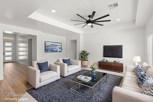 Living room with a tray ceiling, a ceiling fan, recessed lighting, and wood finished floors