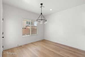 Spare room with light wood-type flooring, a chandelier, and recessed lighting