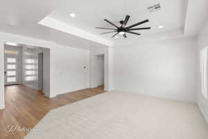 Spare room with a ceiling fan, a raised ceiling, recessed lighting, healthy amount of natural light, and wood finished floors