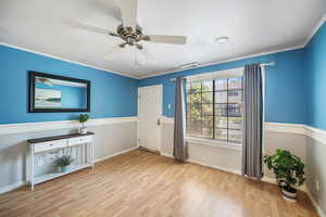 Foyer entrance featuring wood finished floors, a ceiling fan, and ornamental molding