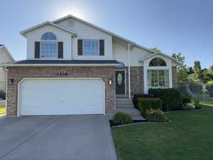 Traditional-style home featuring concrete driveway, brick siding, and a garage