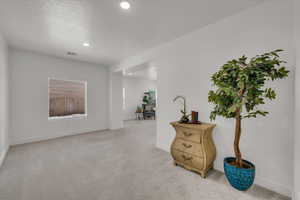 Empty room with light colored carpet and recessed lighting