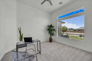Carpeted home office with ceiling fan and baseboards