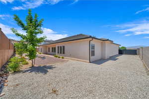 Rear view of property with stucco siding, a fenced backyard, and a patio area
